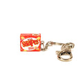 A miniature keychain shaped like a box of Arnott's Chicken Crimpy Shapes , featuring an orange and yellow snack box design attached to a silver metal split ring and clasp, on a plain white background.