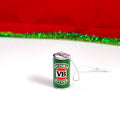 A miniature silver can-shaped Christmas tree ornament featuring the green, red, and white Victoria Bitter logo, resting on a white surface with a red and green tinsel backdrop.