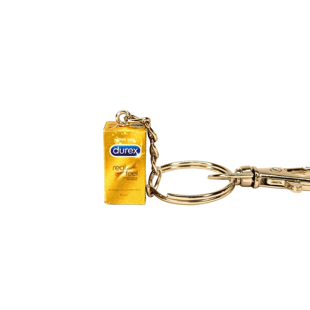 A novelty keychain shaped like a miniature Durex Real Feel condom box, attached to a silver metal split ring and clasp, on a plain white background.