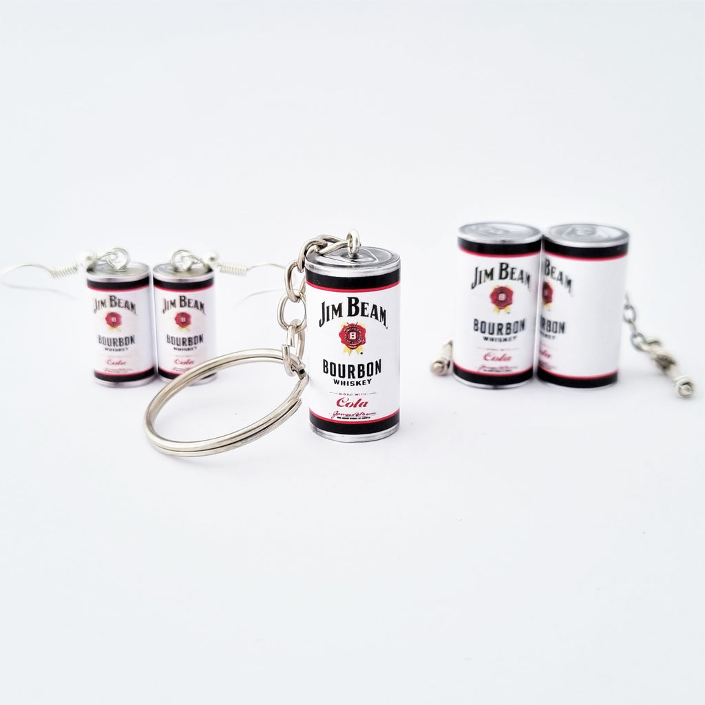 A miniature Jim Beam Bourbon Whiskey keychain arranged on a clean white background, with a pair of Jim Beam earrings behind and to the left and a pair of Jim Beam cufflinks behind and to the right, each designed to look like a small whiskey can with a silver metal key ring attached.
