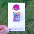A hand holds a Cheeky Little Monkeys backing card featuring an Oh The Places You'll Go book pin.