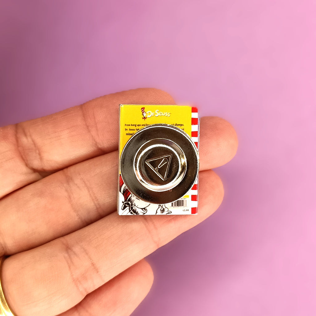 A hand holding a miniature Dr. Seuss-themed magnet brooch