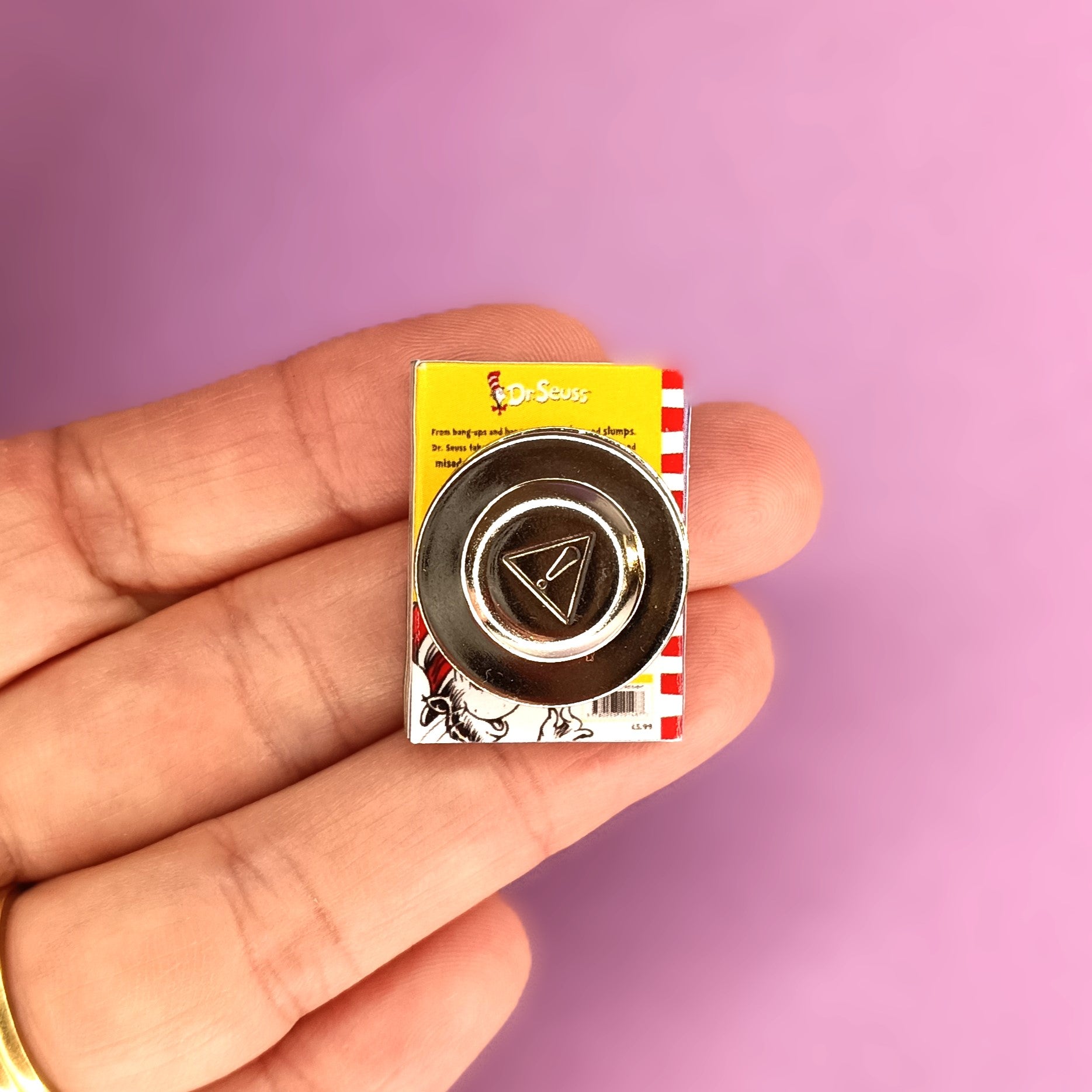 A hand holding a miniature Dr. Seuss-themed magnet brooch