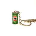 A miniature keychain shaped like a vintage green Victoria Bitter can, featuring the classic red and white VB logo, attached to a silver metal split ring and chain on a white background.