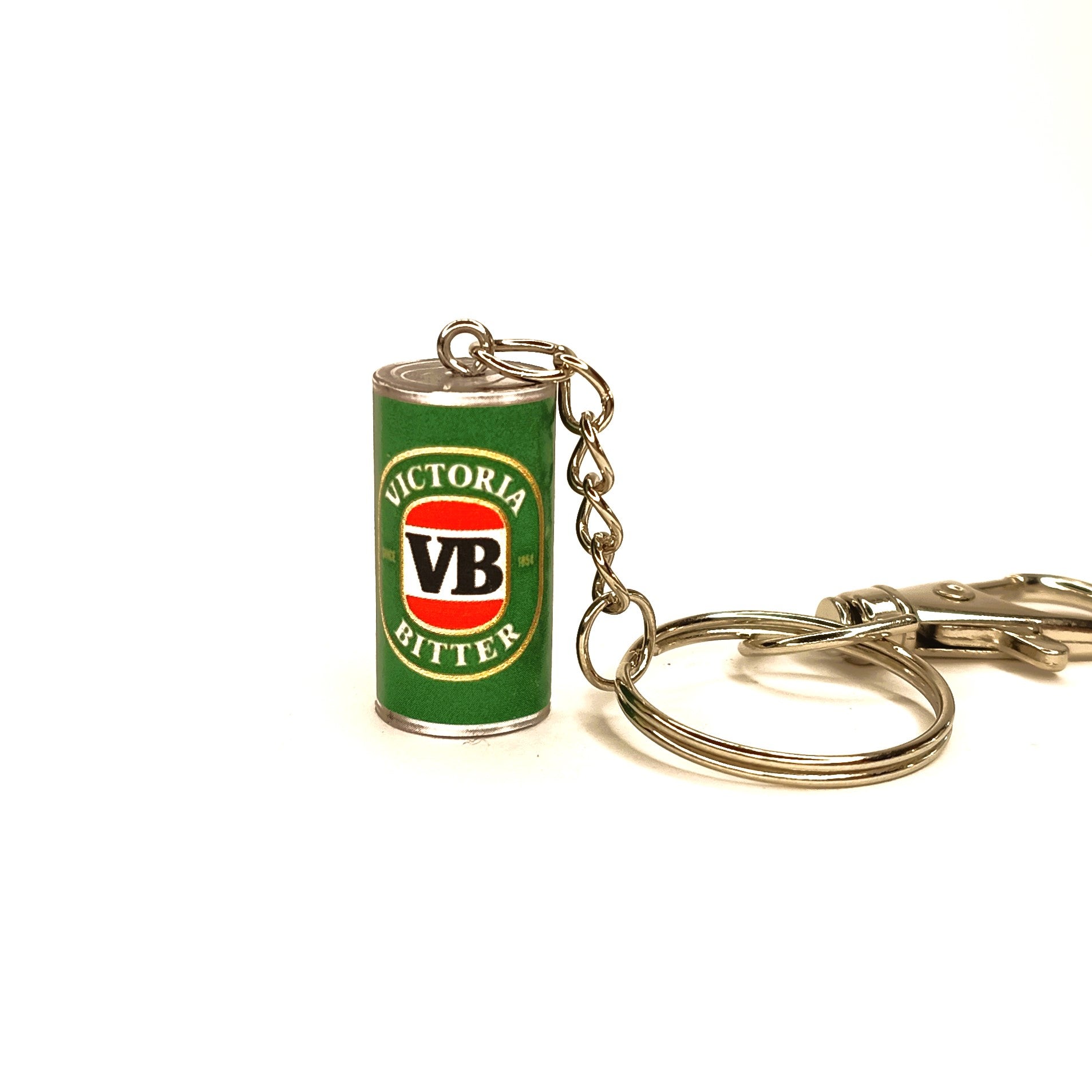 A miniature keychain shaped like a vintage green Victoria Bitter can, featuring the classic red and white VB logo, attached to a silver metal split ring and chain on a white background.