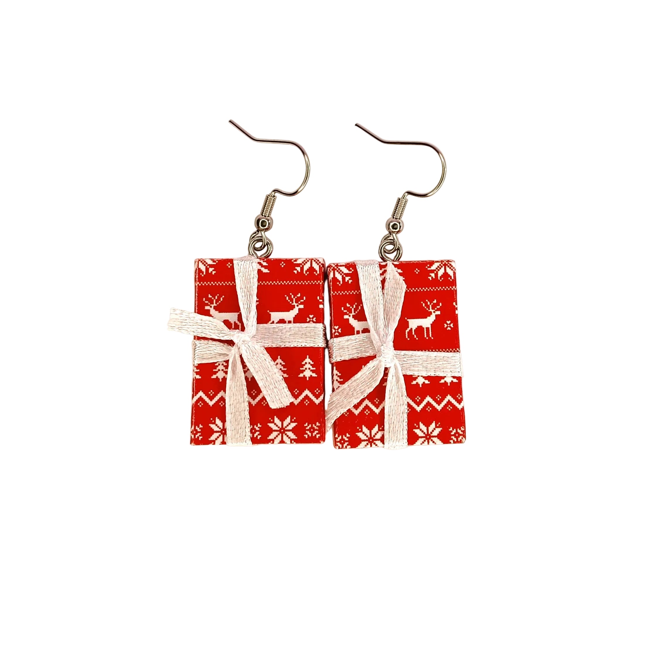 A pair of dangle earrings shaped like wrapped Christmas presents, featuring red gift boxes with white holiday patterns and white ribbon bows, suspended from silver fishhook ear wires on a plain white background.