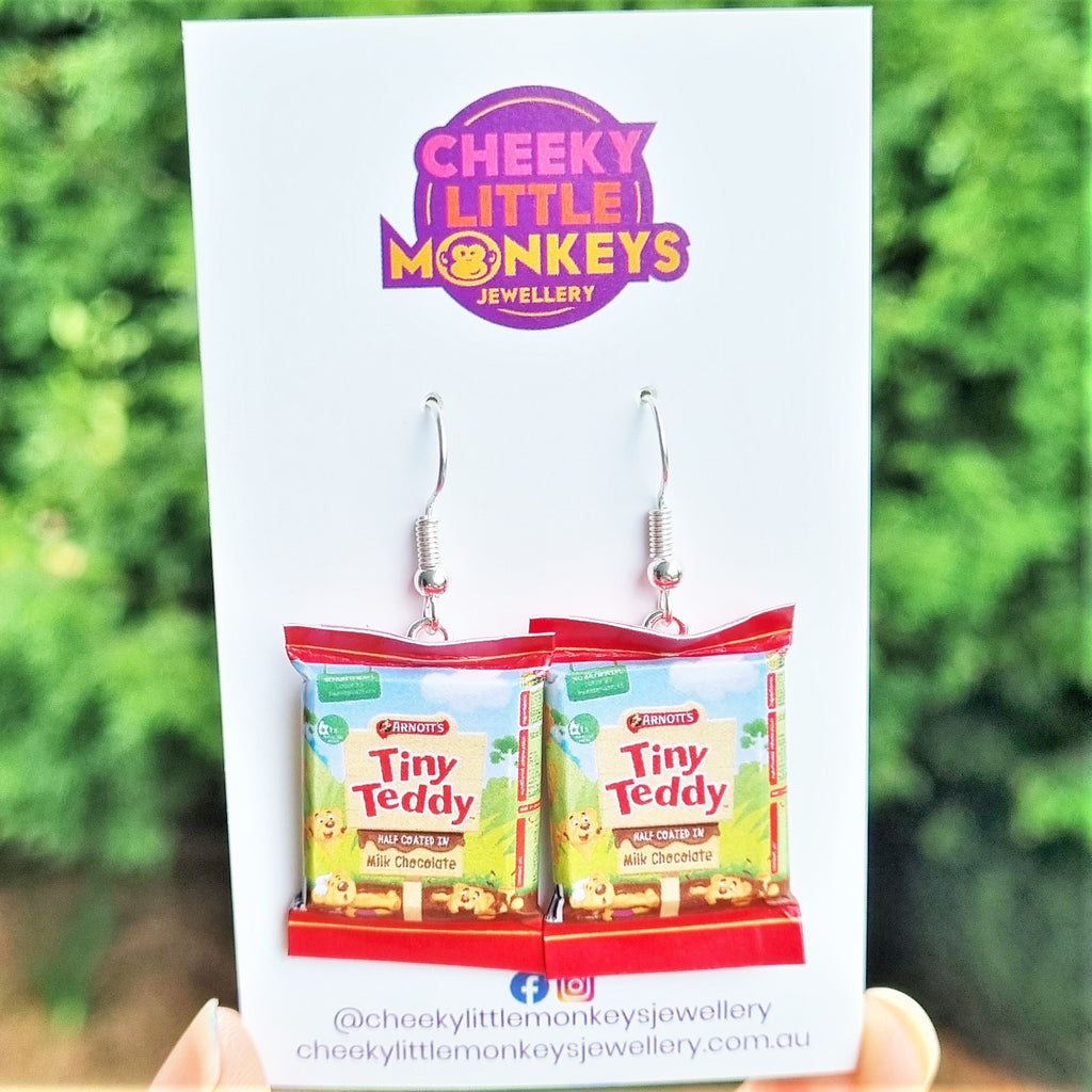 A pair of earrings designed to resemble Tiny Teddy biscuit packets, displayed on a card with the brand name Cheeky Little Monkeys Jewellery.